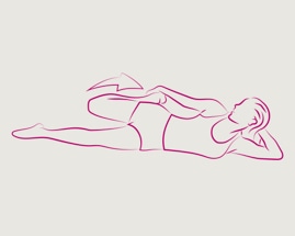 Žena leží na jednej strane a priťahuje hornú nohu, aby precvičila stehenný sval.